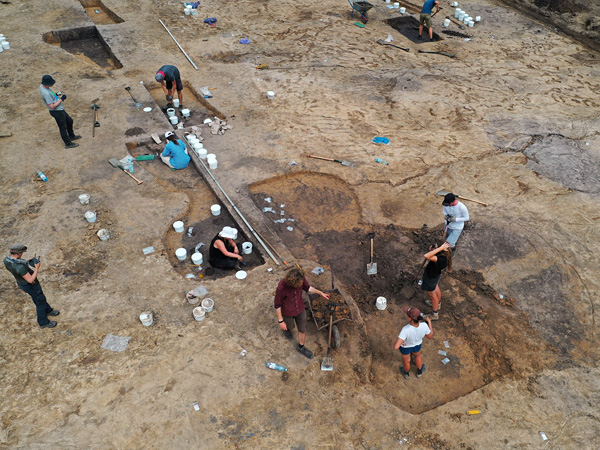 View from above of several people digging soil out of holes or taking samples