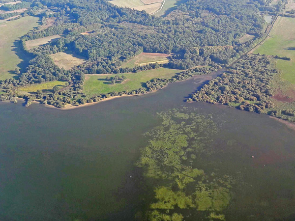 Aerial view of a part of a water reservoir. The dark green water surface is covered in places with light green spots