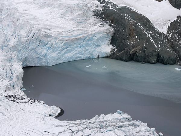 The frozen water surface of a small bay surrounded by a rocky and icy shore